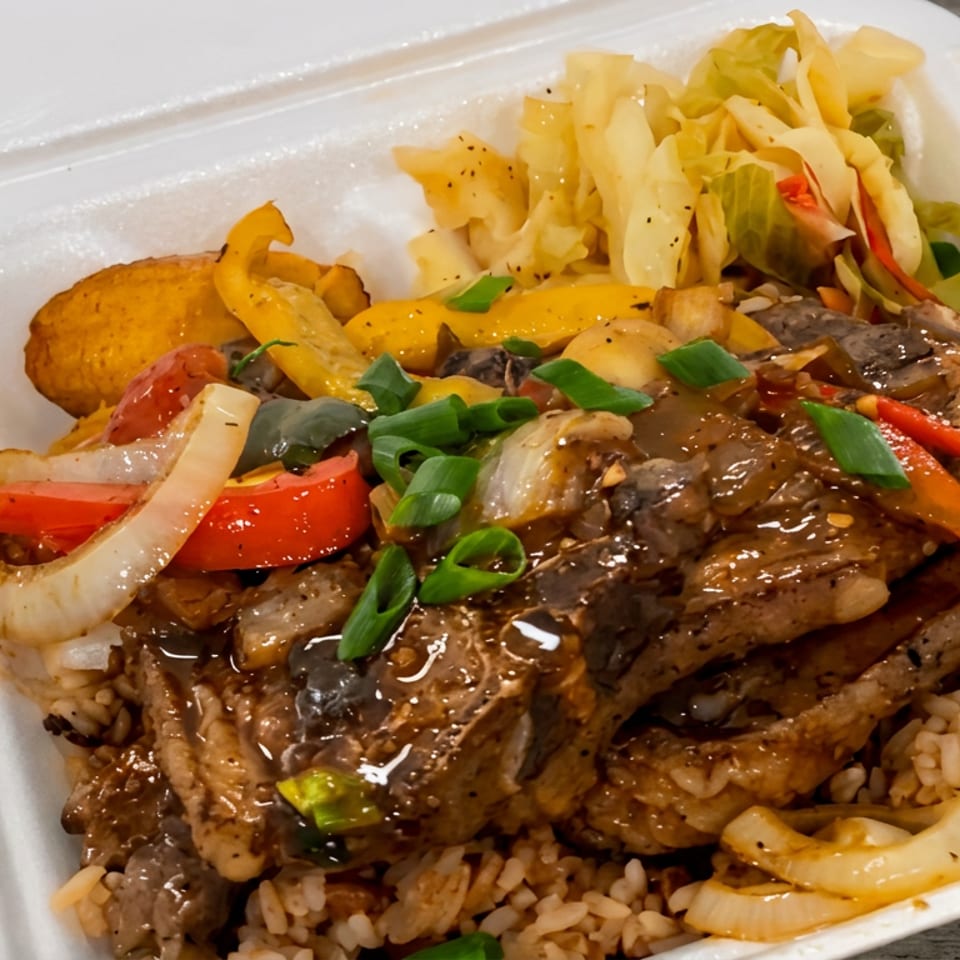 Open takeout container filled with saucy grilled meat, peppers, onions, rice, potatoes, and mixed vegetables.