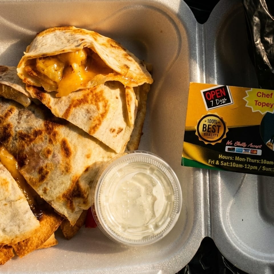 Open takeout container holding grilled cheesy quesadilla wedges with dipping sauce and a Chef Topey business card.